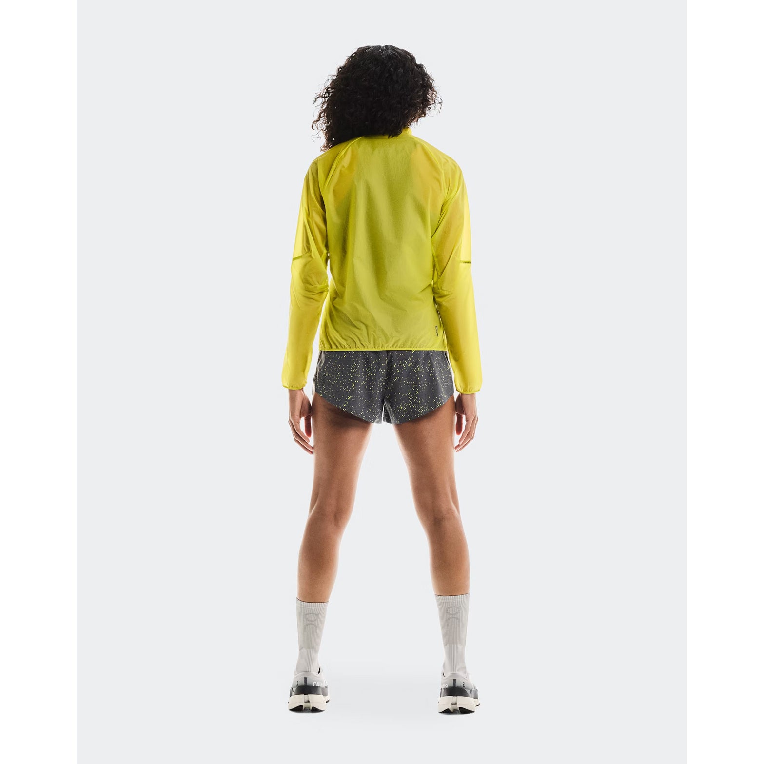 Women's On Zero Jacket Lime full body back view on female runner showing breathable lightweight construction with reflective elements for low-light visibility