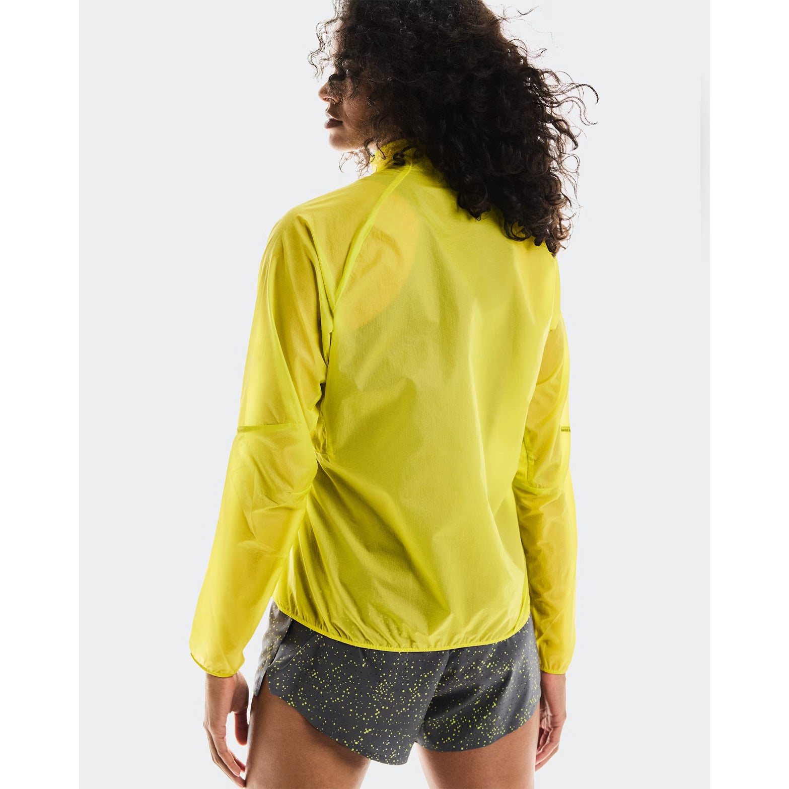Women's On Zero Jacket Lime back view on female runner showing breathable windproof fabric with reflective details for visibility