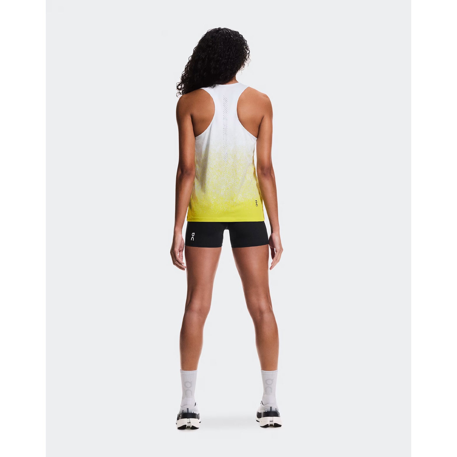 Women's On Zero Singlet White Yellow full body back view on female runner showing athletic racer-back styling and reflective detail for visibility