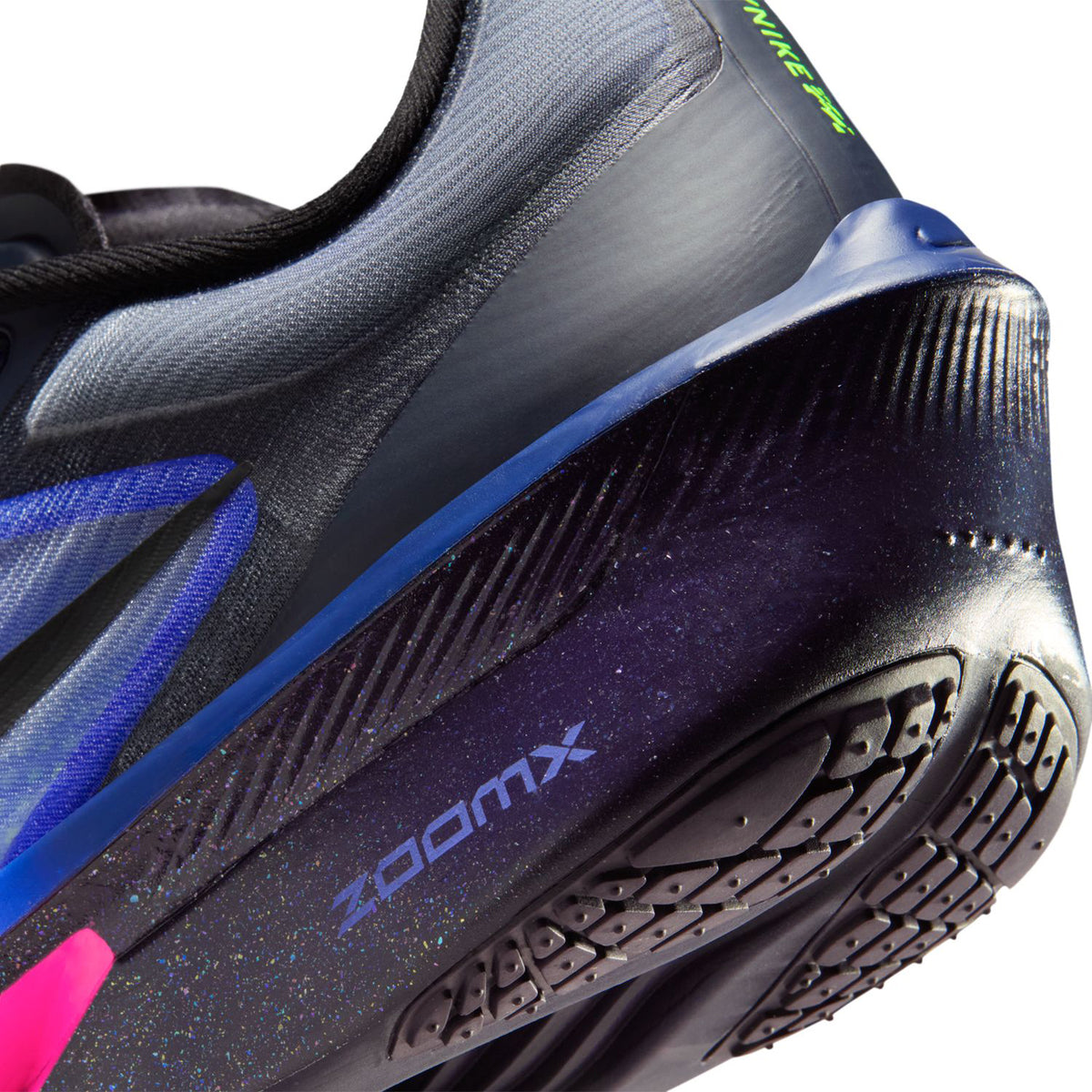 Close-up of the heel and sole of a running shoe with ZOOMX branding, featuring black, blue, and purple colors, textured grip, and neon green and pink accents.